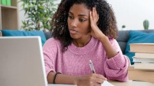 Woman learning digital marketing online. Student with laptop and books.